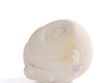 une sculpture blanche représentant un chat posée sur une surface blanche
