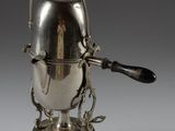 une cafetière ancienne en argent, munie d'une anse et posée sur un socle