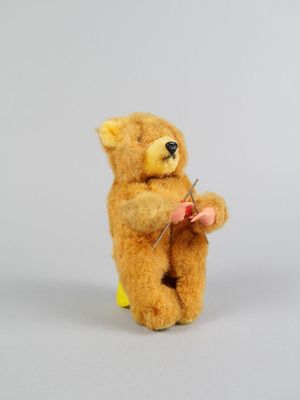 un ours en peluche qui tient une aiguille entre ses pattes