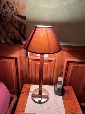 une petite table sur laquelle est posée une lampe, à côté d'un lit