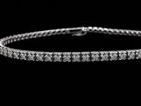 a diamond tennis bracelet on a black background