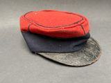 un chapeau rouge et noir posé sur une surface grise