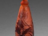 un vase rouge orné d'un motif sur un fond gris