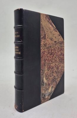 an old book with a black cover sitting on top of a white table