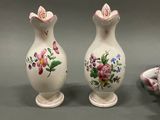 two vases with flowers painted on them sitting on a table