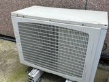 a white air conditioner sitting on the ground next to a wall