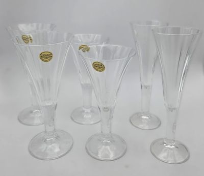 four clear wine glasses with gold rims on a white surface