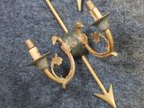 two antique brass wall sconces with arrows on a blue background