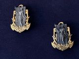 two silver and gold pin badges with a man and woman on them