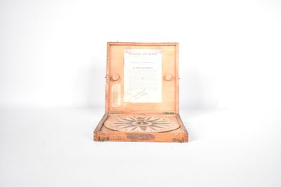 une petite boîte en bois sur laquelle est représentée une boussole