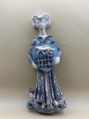une figurine représentant une femme tenant un panier rempli de nourriture