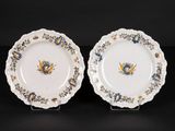 two white plates with blue and yellow designs on them on a black surface