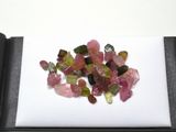un tas de tourmalines roses et vertes posées sur une surface blanche