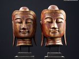 deux statues en bois représentant des visages de Bouddha sur fond noir