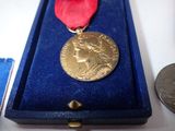 a gold medal with a red ribbon in a blue box