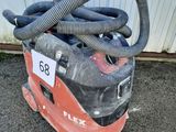un aspirateur posé par terre, muni d'un tuyau