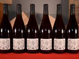 six bouteilles de vin rouge sont alignées sur une table