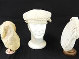 trois chapeaux blancs et un porte-chapeaux sur fond noir