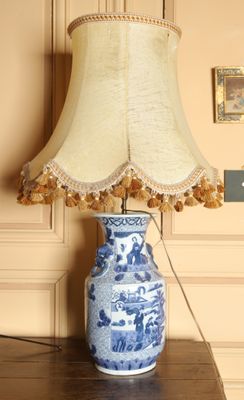 un vase bleu et blanc posé sur une table, sur laquelle se trouve une lampe