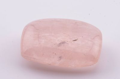 une pierre de quartz rose posée sur une surface blanche