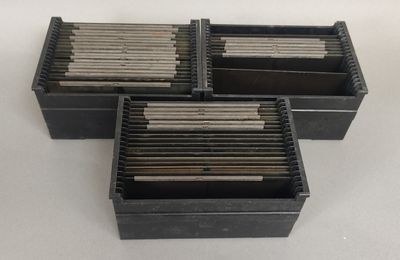 three black boxes with metal rods in them sitting on a table