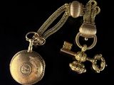 an image of a gold pocket watch and key on a black background