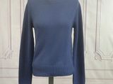 the blue sweater is on a mannequin stand in front of a white wall