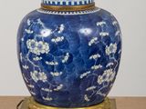 a blue and white vase with a gold base on a table