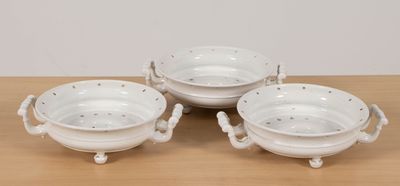 three white porcelain bowls with handles and handles on a wooden table