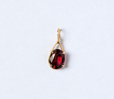 un gros plan d'un pendentif en pierre rouge posé sur une surface blanche