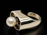 an image of a ring with a pearl in it on a black surface
