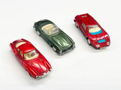 trois petites voitures assises l'une à côté de l'autre sur une surface blanche
