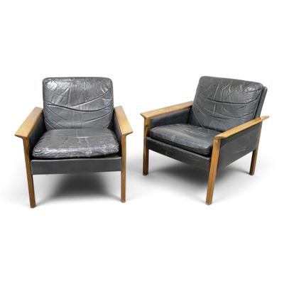 pair of black leather lounge chairs with wooden arms