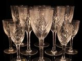 seven crystal wine glasses are lined up in a row on a black surface