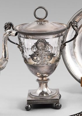 un plateau en argent orné d'un paon, à côté d'une coupe en argent