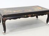 une table basse noire avec un plateau et des pieds peints