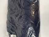 un gros plan sur un sac contenant des vêtements noirs posé sur une surface blanche