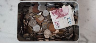 un récipient métallique rempli de pièces et de billets posé sur une table