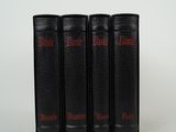 trois livres noirs portant des inscriptions rouges, posés sur une surface blanche