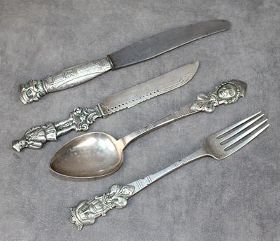 un service d'argenterie composé d'un couteau, d'une fourchette et d'une cuillère posés sur une table