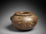 a brown vase sitting on top of a table next to a black background