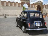 a small black car parked in front of a building