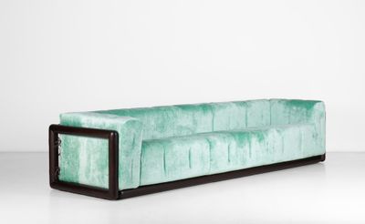 une photo d'un canapé vert avec des pieds noirs et une structure en bois