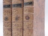 trois vieux livres posés l'un sur l'autre sur une surface blanche