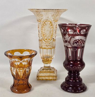 three different colored glass vases sitting next to each other on a white surface