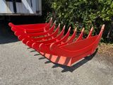 six canoës rouges alignés au bord de la route