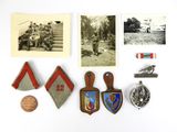 Plusieurs insignes et épinglettes militaires sont disposés sur un fond blanc