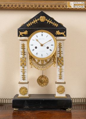 une horloge posée sur une table devant un tableau