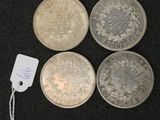four silver coins and a tag on a black surface