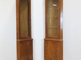 pair of tall wooden display cabinets with glass doors in a white room